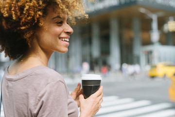 Happy woman walking with coffee in the city