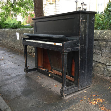 Old piano left standing by the roadside.
