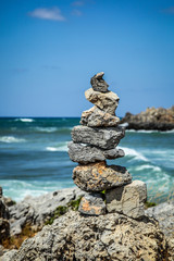 Fototapeta na wymiar Pyramid of stones on the sea and sky background