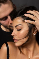 Closeup of a beautiful couple. A man sensually touches his lips to the forehead of a girl whose shoulder is bare. Casual fashionable style. Lifestyle, fashion, commercial design