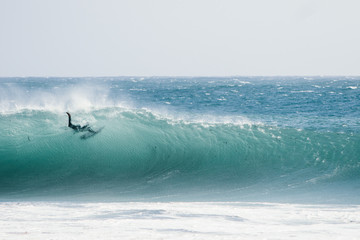 A male surfer pushes himself through a breaking wave.