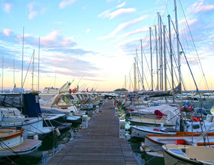 ALASSIO (SAVONA), ITALY - SEPTEMBER 2017: Luxury yachts and sailboats in seaport at sunset. Marine parking of modern motorboats in Liguria, Italia