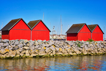 Four red fisher houses behind the stone groyne at the harbor Weiße Wiek in Boltenhagen at the Baltic Sea. Germany