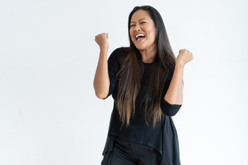 Joyful middle-aged woman celebrating success. Lady pumping fists with her eyes closed. Success concept. Isolated front view on white background.