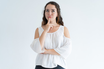 Portrait of pensive young woman standing with hand on chin. Young Caucasian girl dreaming about...