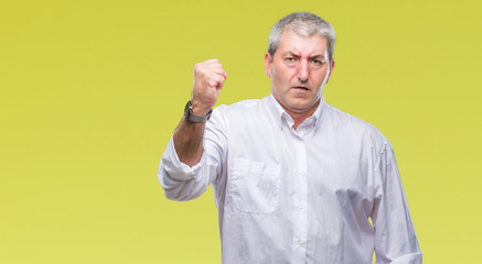 Handsome senior man over isolated background angry and mad raising fist frustrated and furious while shouting with anger. Rage and aggressive concept.