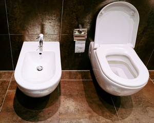 Open ceramic toilet bowl with bidet in bathroom