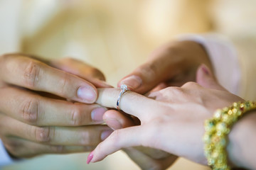 Wedding rings. He Put the Wedding Ring on Her. Close up Groom Put the Ring on bride. thai wedding ceremony and thai wedding decoration.