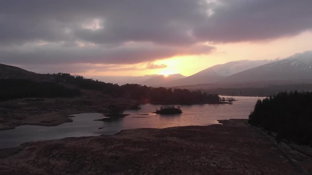 Aerial drone shot of sunset behind mountains and Loch Tulla near Glencoe, Highlands of Scotland