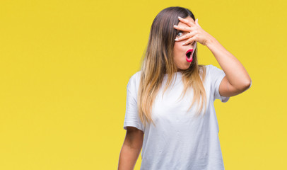 Young beautiful woman casual white t-shirt over isolated background peeking in shock covering face and eyes with hand, looking through fingers with embarrassed expression.