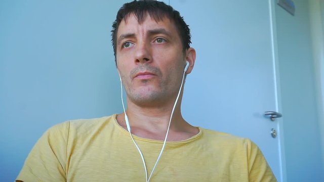 Man in headphones listening to music in a bright room. 1920X1080 Full Hd.