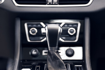 Selector automatic transmission with perforated leather in the interior of a modern expensive car. The background is blurred