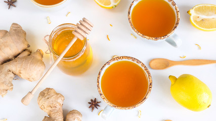 Tea with turmeric among products for improving immunity and treating colds - ginger, lemon and a jar of honey with a wooden spoon