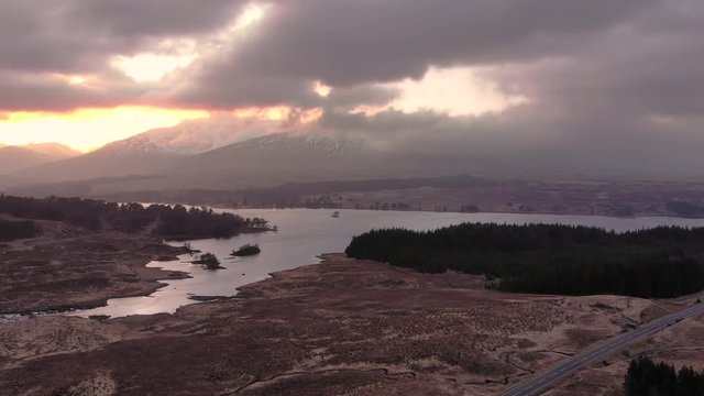 Aerial drone shot of sunset behind mountains and Loch Tulla near Glencoe, Highlands of Scotland