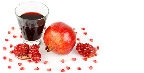 Pomegranate juice in a glass and ripe pomegranates. Isolated on white background. Free space for text. Wide photo.