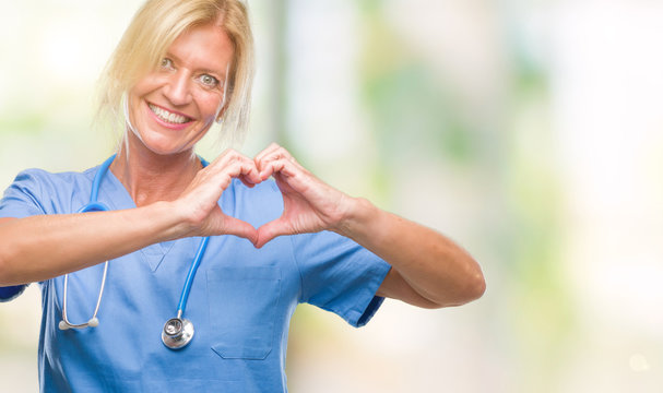Middle age blonde nurse surgeon doctor woman over isolated background smiling in love showing heart symbol and shape with hands. Romantic concept.