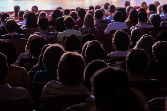 Spectators at a theater performance, in a cinema or at a concert. Shooting from behind. The audience in the hall. Silhouettes of people.