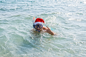 Man in a Santa Claus hat and diving mask, Christmas background with copy space.