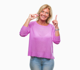 Fototapeta na wymiar Middle age blonde woman eatin pink macaron biscuit over isolated background surprised with an idea or question pointing finger with happy face, number one