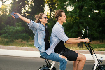 Lovely young couple driving electric bike during summer Modern city life and transportation