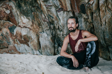 Crazy guy climbing on a rock and relaxing on the beach