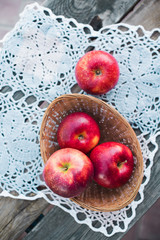 Autumn harvest. Red ripe apples in a wicker basket on a knitted napkin on a table in the garden on a Sunny day. Rustic style	