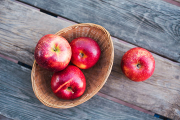 Autumn harvest. Red ripe apples in a wicker basket on a table in the garden on a Sunny day. Rustic style