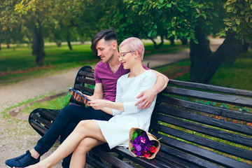 Relationship. A guy and a girl walk and smile in the Park. A young couple reading a book in the Park on a Sunny summer day.	