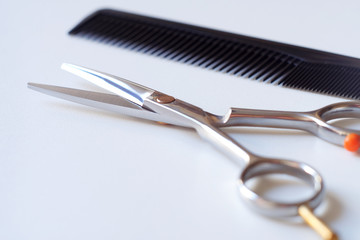 Scissors with finger rest on ring and comb isolated on white background.