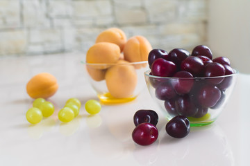 Bowl of apricots and a bowl of cherries on a bright table in the Studio. Healthy food.