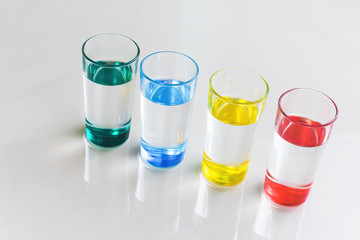 Water in transparent glasses with colored bottom on the table in the room.