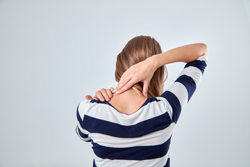 Young woman with upper back pain holding spine.
