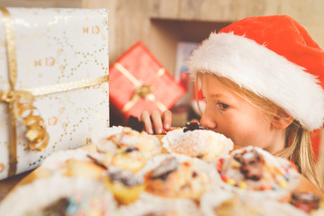 Young girl, primary school age, looking at plate full of big colourful muffins