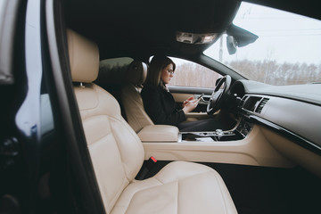 Young attractive blonde uses phone while sitting in car