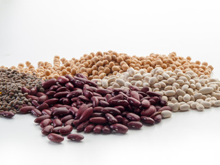 Un puñado de alubias rojas y blancas, lentejas y garbanzo vistos frontalmente sobre un fondo blanco