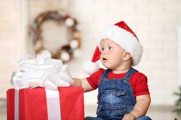 Fototapeta na wymiar Baby boy in santa hat with gift box sitting at home