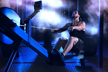 Bearded fit man using rowing machine at functional training