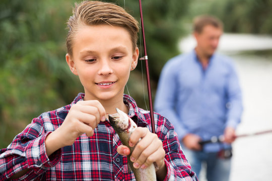teenager boy holding catch fish on hook  .