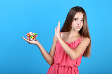 Young girl with bowl of candies on blue background