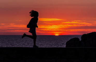 girl is running in front of the sunset in Penmarch, France