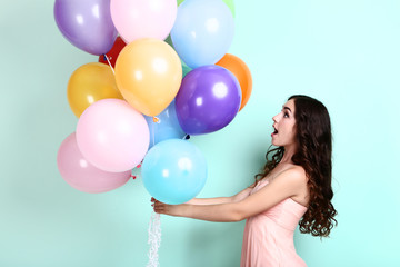 Obraz premium Young girl with colored balloons on mint background