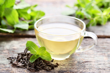 Cup of tea with mint leafs on grey wooden table