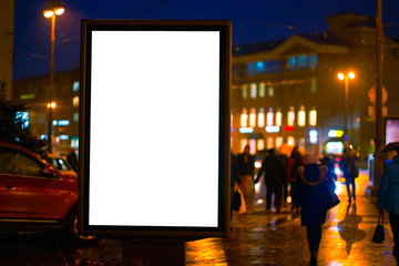 the billboard ad night city, shines in the night city. mockup with a white field for advertising. rainy evening, wet weather and road