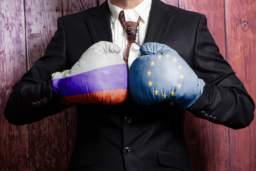 Businessman in boxing gloves with Russian and European Union flag. Russia versus European Union...