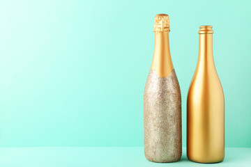 Decorated champagne bottles on mint background