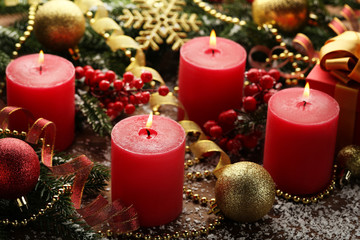 Christmas candles with fir-tree branches and baubles on wooden table