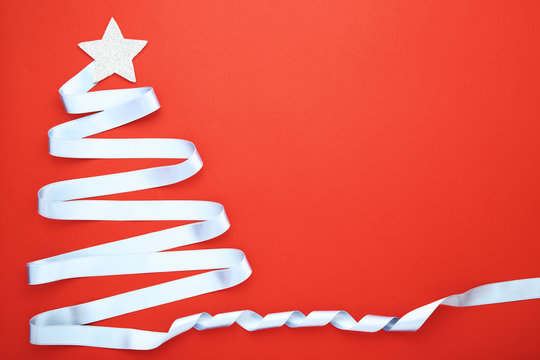 Blue ribbon in shape of christmas tree on red background