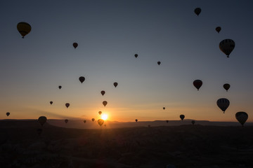 Hot air balloons in the sky during sunrise. Flying over the valley at Cappadocia, Anatolia, Turkey. Volcanic mountains in Goreme national park.