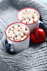 Cappuccino with marshmallows in mugs, red heart and knitted scarf