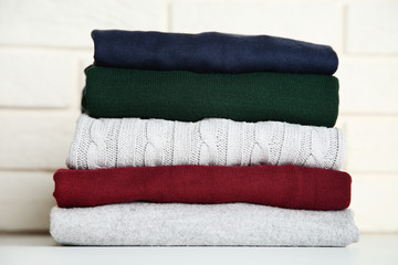 Stack of folded sweaters on brick wall background